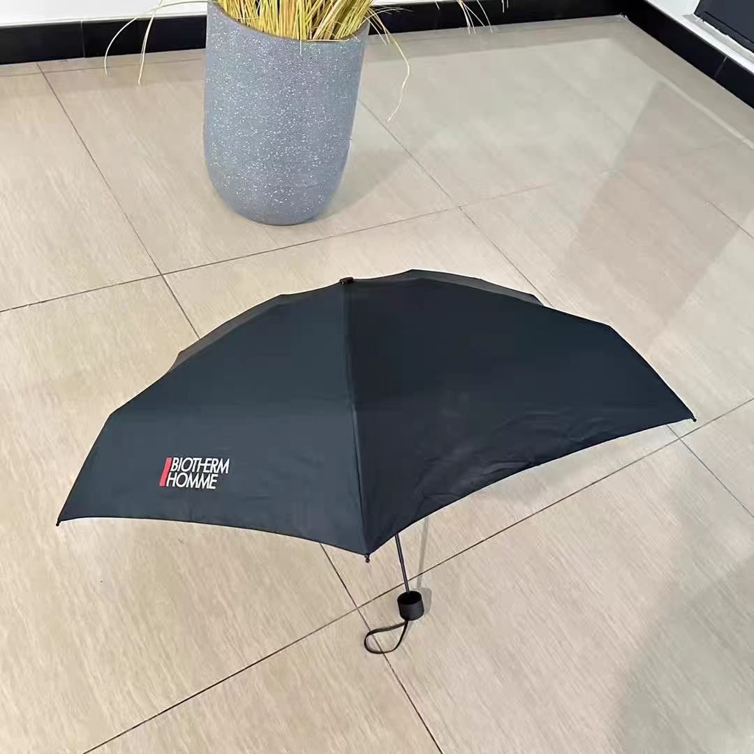 Open black Biotherm Homme branded mini umbrella with white logo